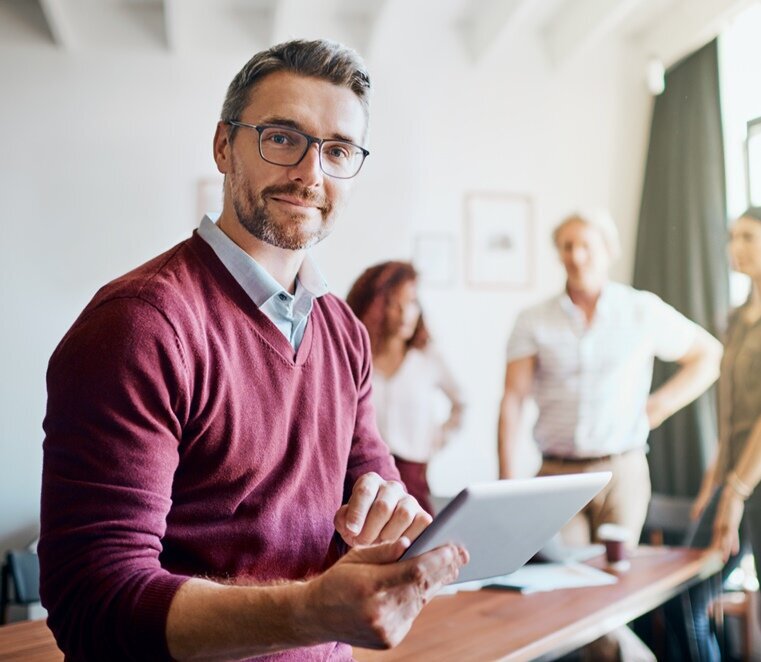 Portrait eines sympatisch lächelnden Teamleader im bordeaux-farbenen Pullover