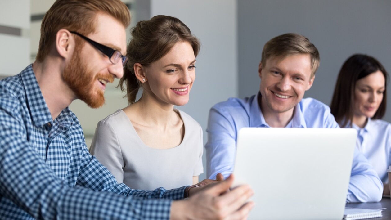 Gruppe junger Mitarbeiter schauen gemeinsam auf einen Laptop