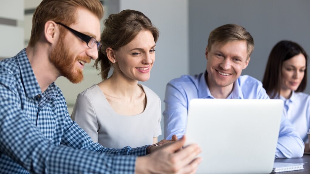 Online-Seminare Gruppe junger Mitarbeiter schauen gemeinsam auf einen Laptop