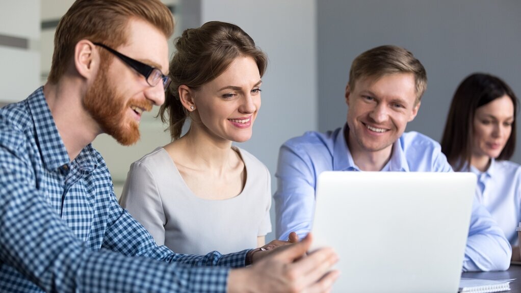 Online-Seminare Gruppe junger Mitarbeiter schauen gemeinsam auf einen Laptop