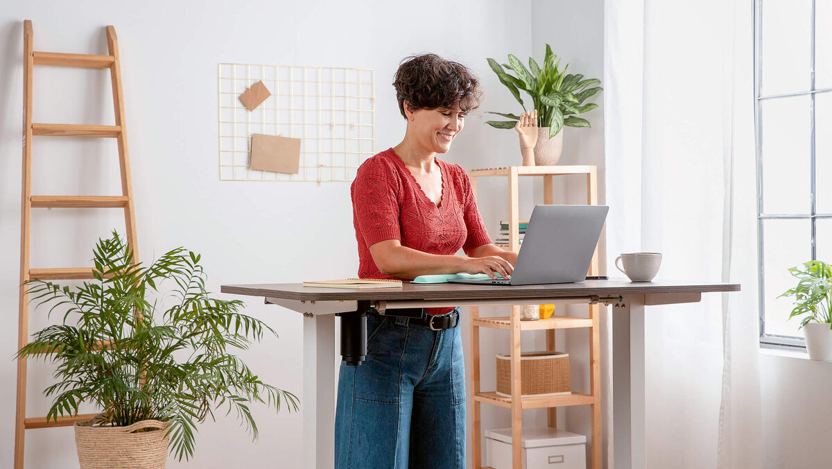 Homeoffice mit ergonomischem Schreibtisch an dem eine Frau arbeitet