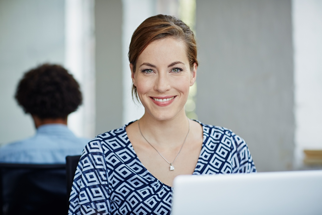 Portrait sympatisch lächelnder Frau vor Laptop