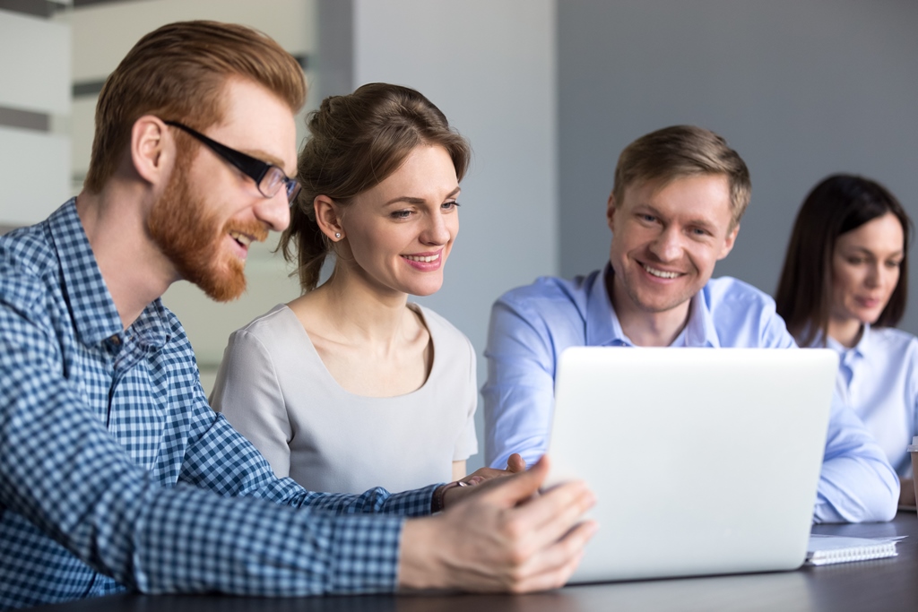 Gruppe junger Mitarbeiter schauen gemeinsam auf einen Laptop