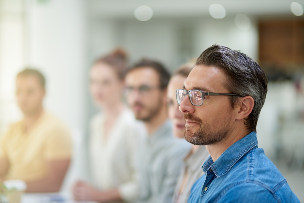 männlicher Seminarteilnehmer im blauen Jeanshemd mit Brille