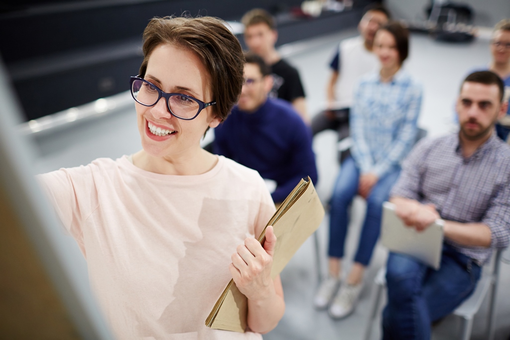 junge Frau mit Brille schreibt am Flipchart